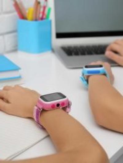 Children with stylish smart watches at white table, closeup